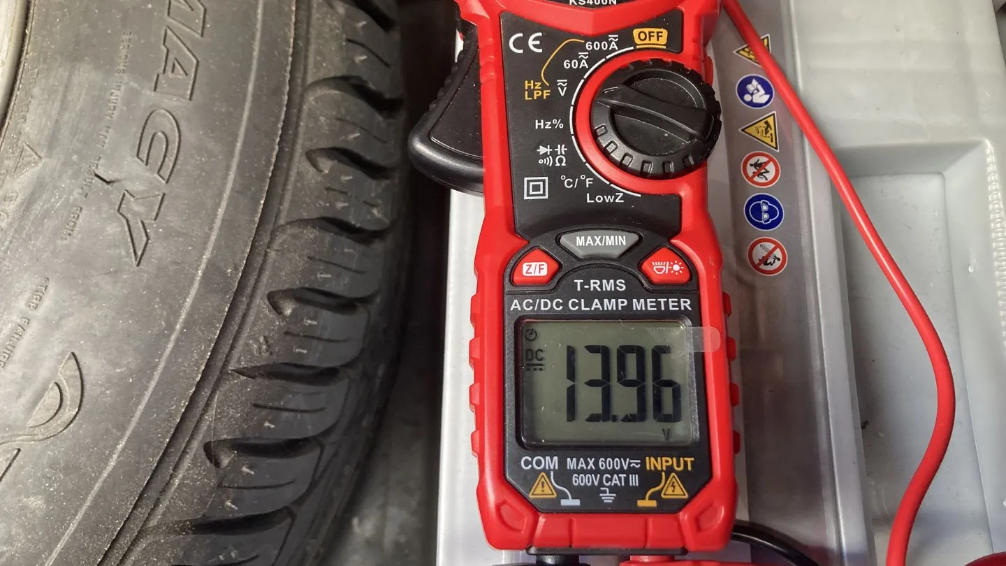 Comprobación del sistema de carga del coche con multímetro marcando 13.96 voltios con el motor en marcha